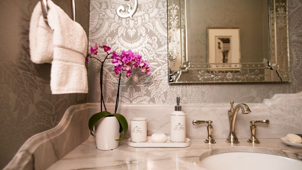 A powder room with two sinks and marble counter top