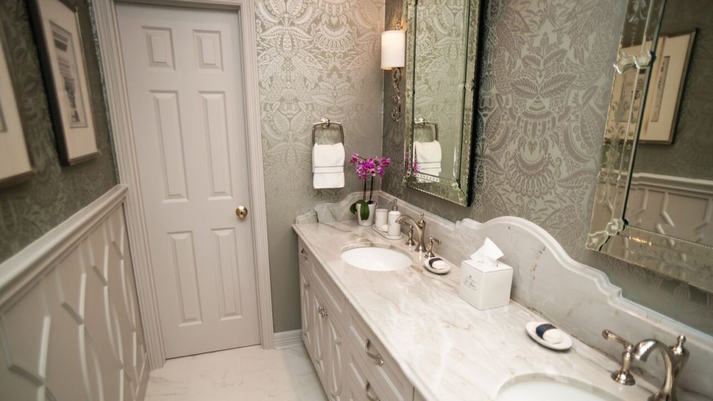 A powder room with two sinks and marble counter top