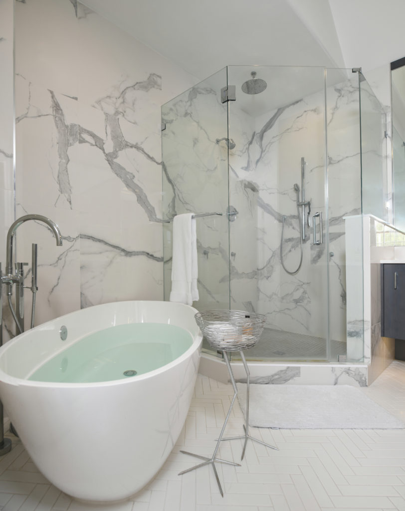 A bathtub and shower area with marble walls